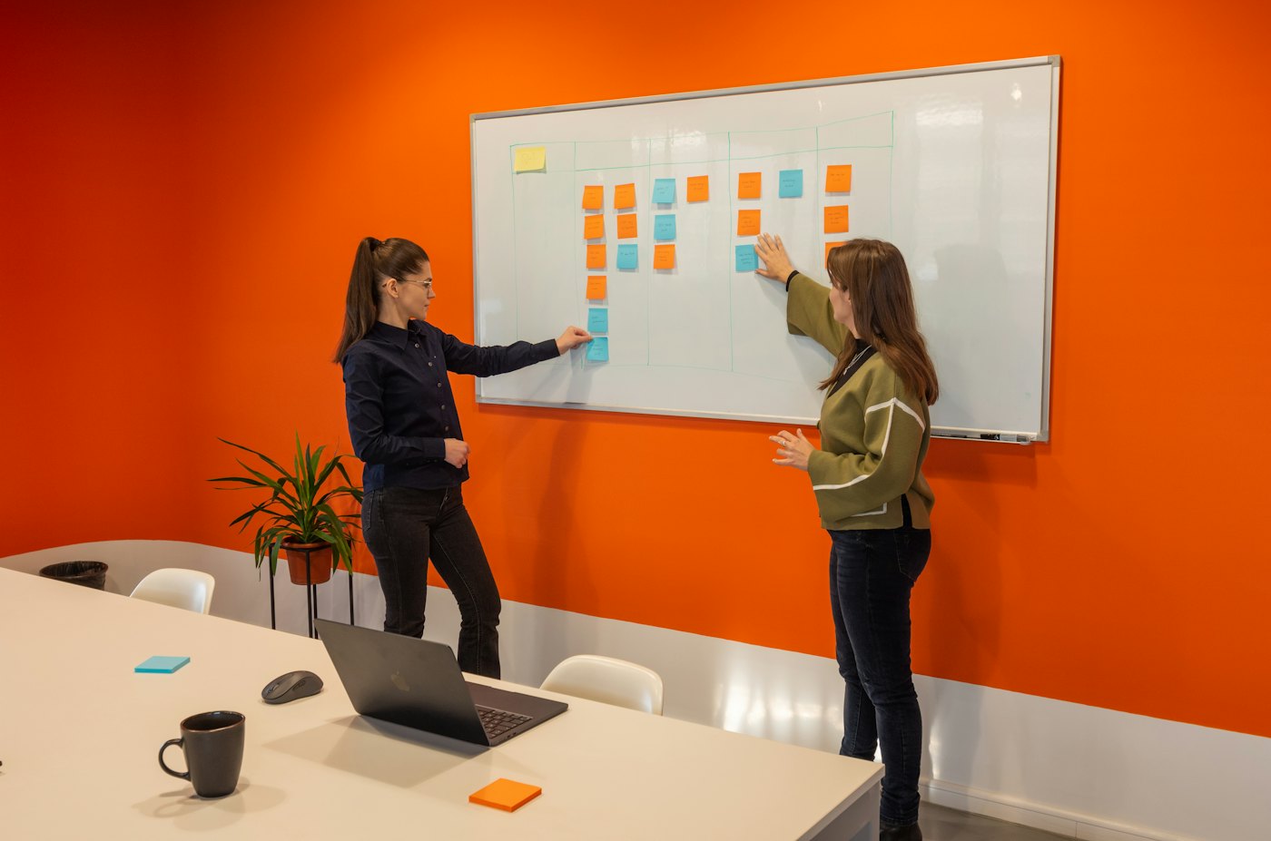 Two people planning on a whiteboard covered in sticky notes